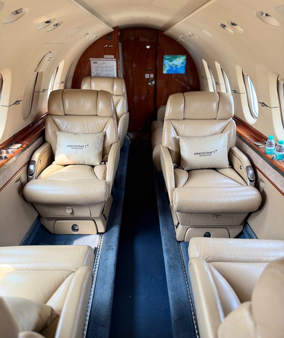 Hawker 900XP cabin with cream leather club seats and wood veneer